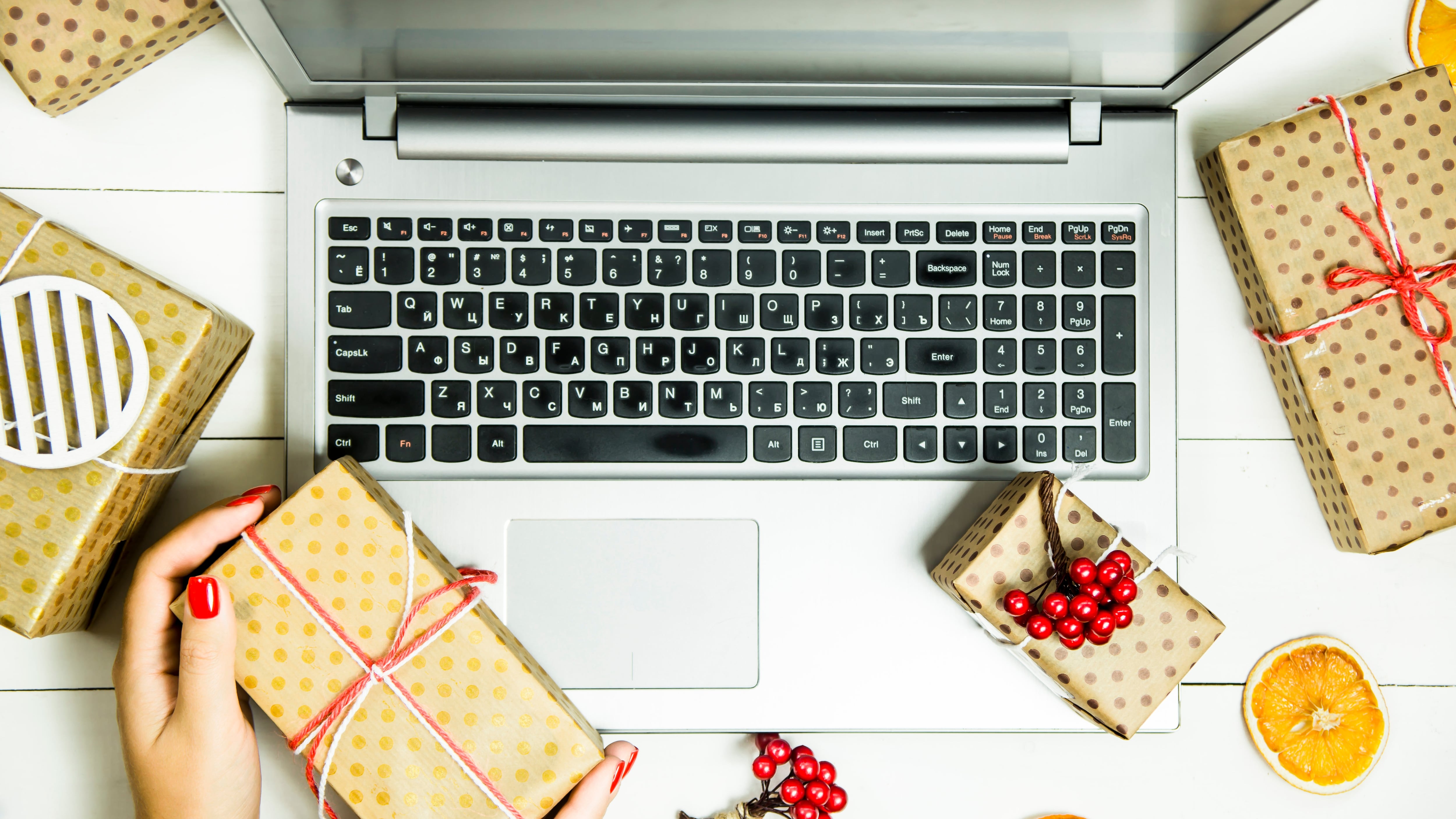 A person on a computer with gifts around them.